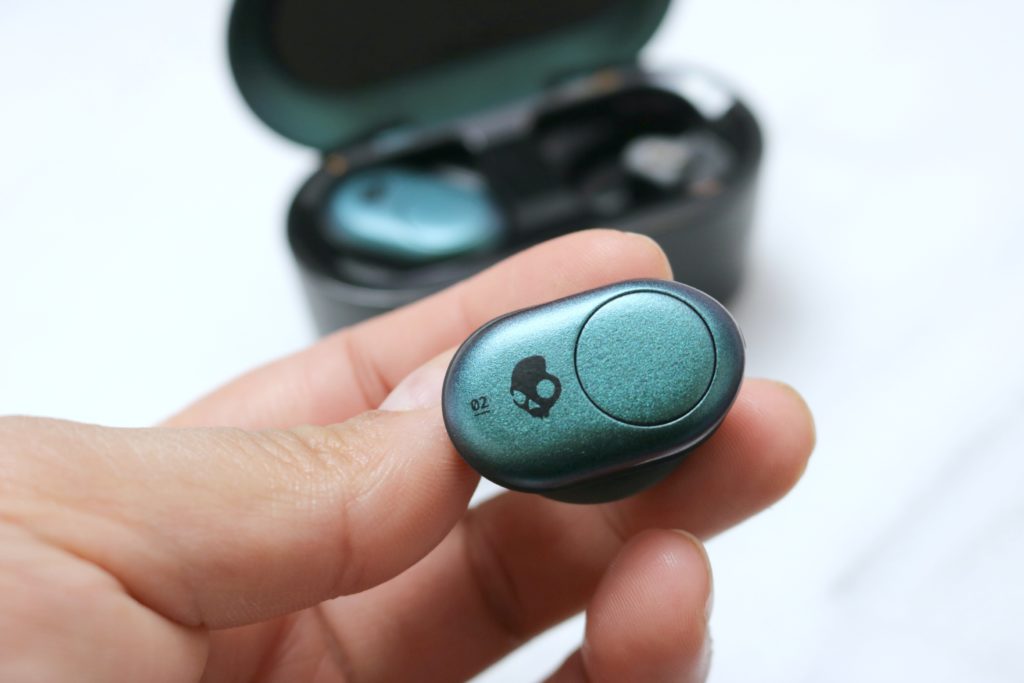Close up view of the Skullcandy Push ear bud and the charging station is in the background. 
