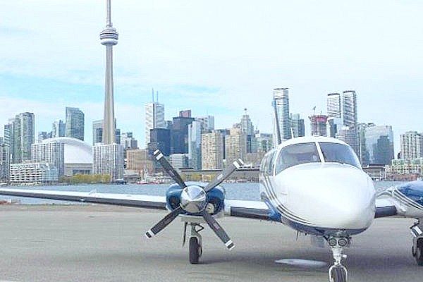 A propeller plane is seen at the airport, behind it is the CN tower. It truly is one of the best experiences to give dad.