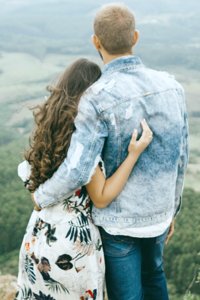 A young couple poses in front of a hillside facing towards the edge.