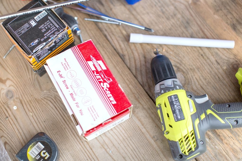 A wooden table with screws, bolts, and a drill gun. All items needed for home maintenance jobs you need to do this summer. 