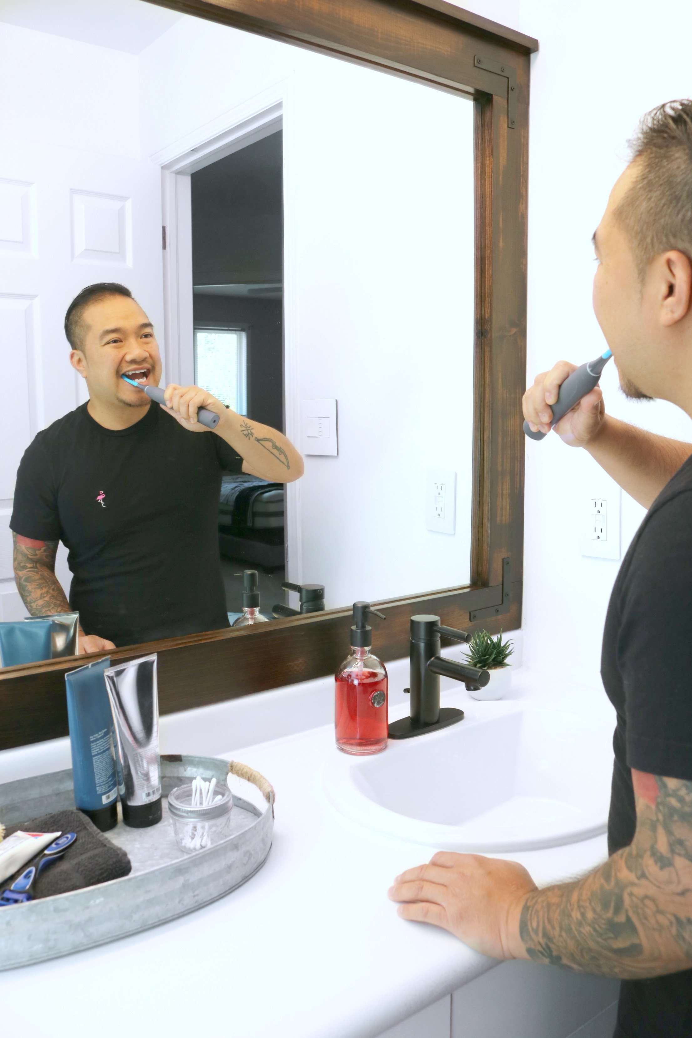 Darasak brushing his teeth in front of mirror with his Cari Pro toothbrush. 