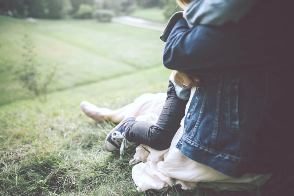 A mom holds her child in a deep hug over a hillside. 