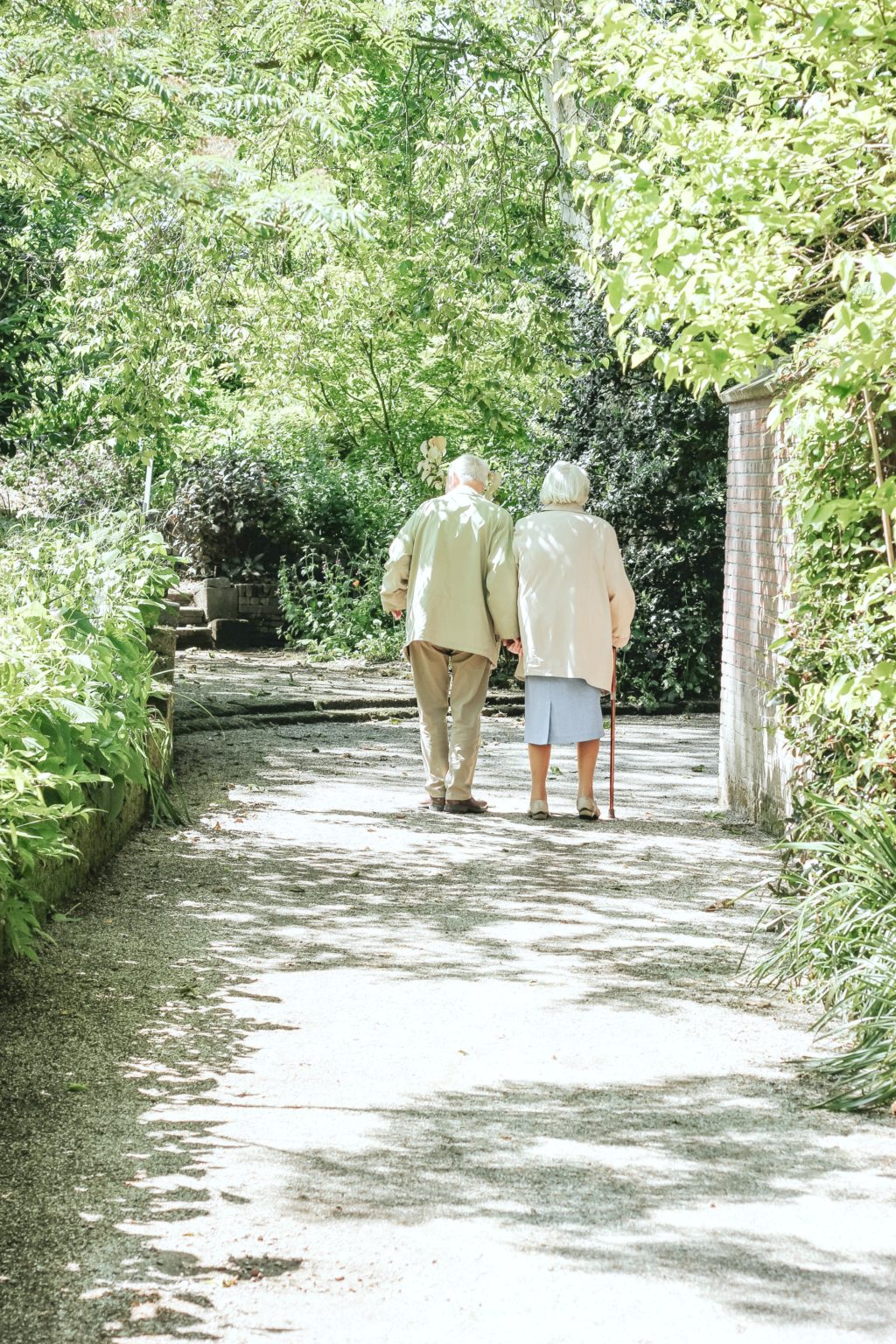 Two elderly people walk along a forested path