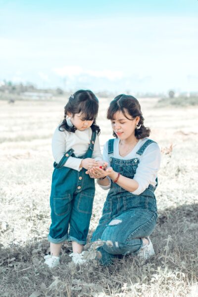 A mother is in a field with her young daughter.