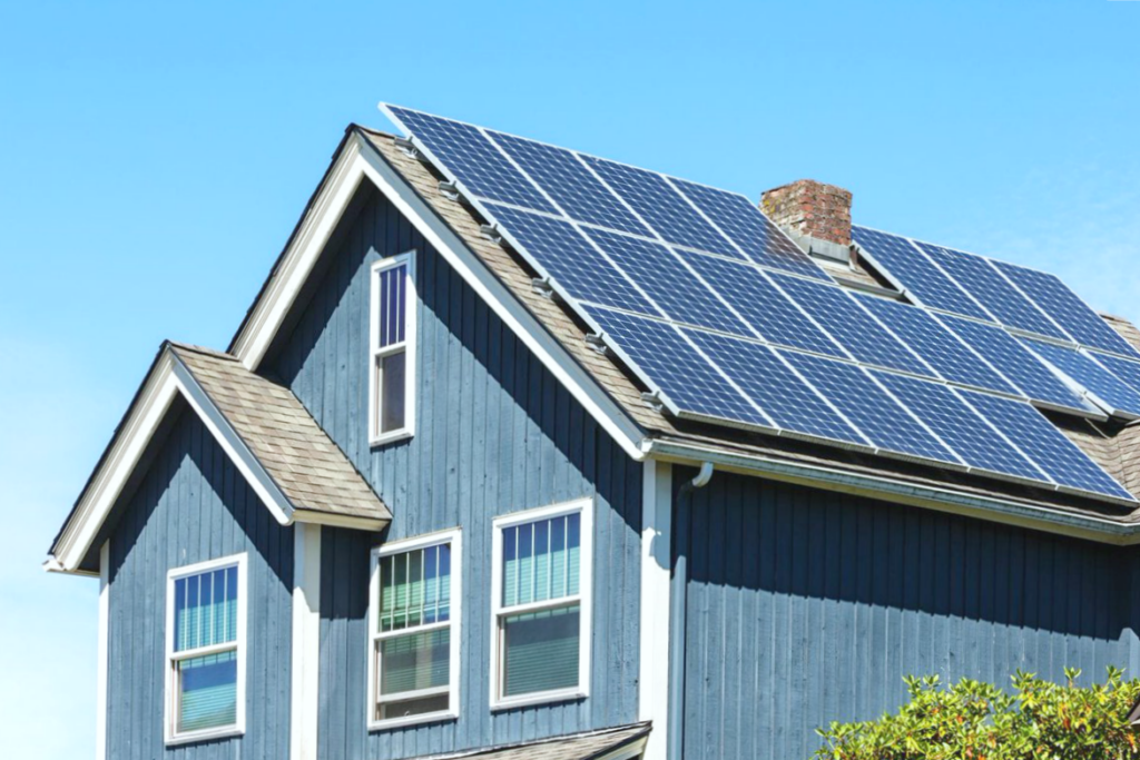 A nice suburban home with solar panels, against a blue sky.