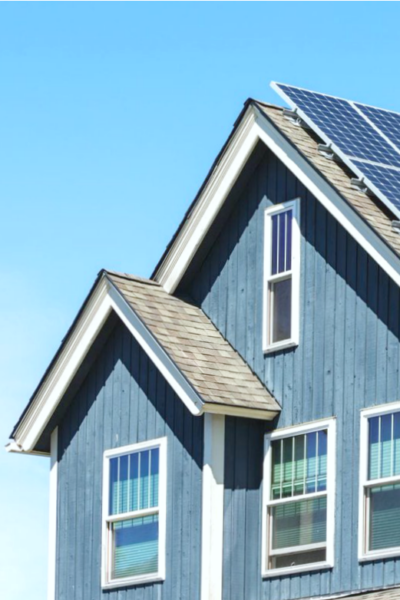A nice suburban home with solar panels, against a blue sky.