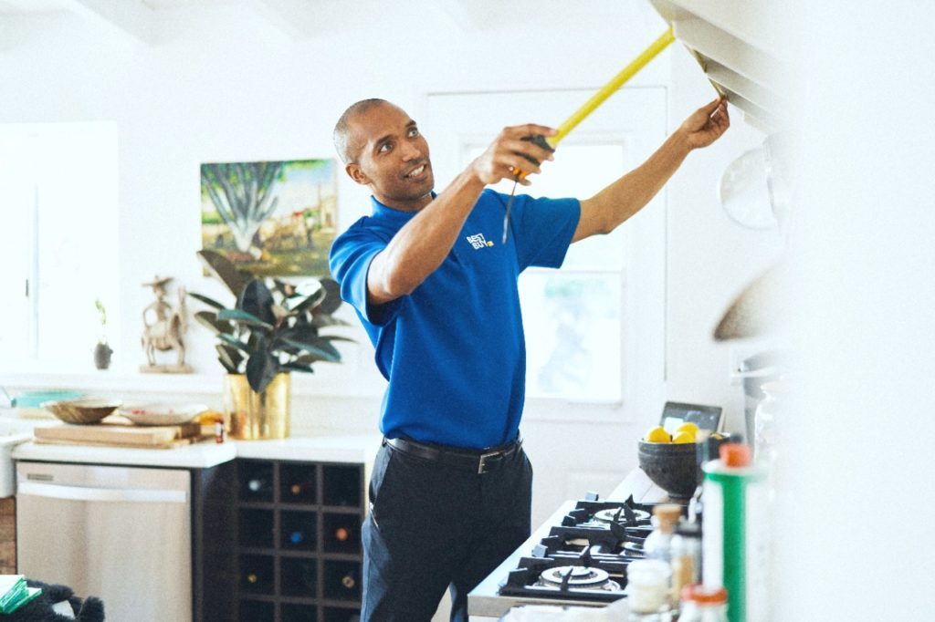 A Best Buy consultant measures a space in a client's home.