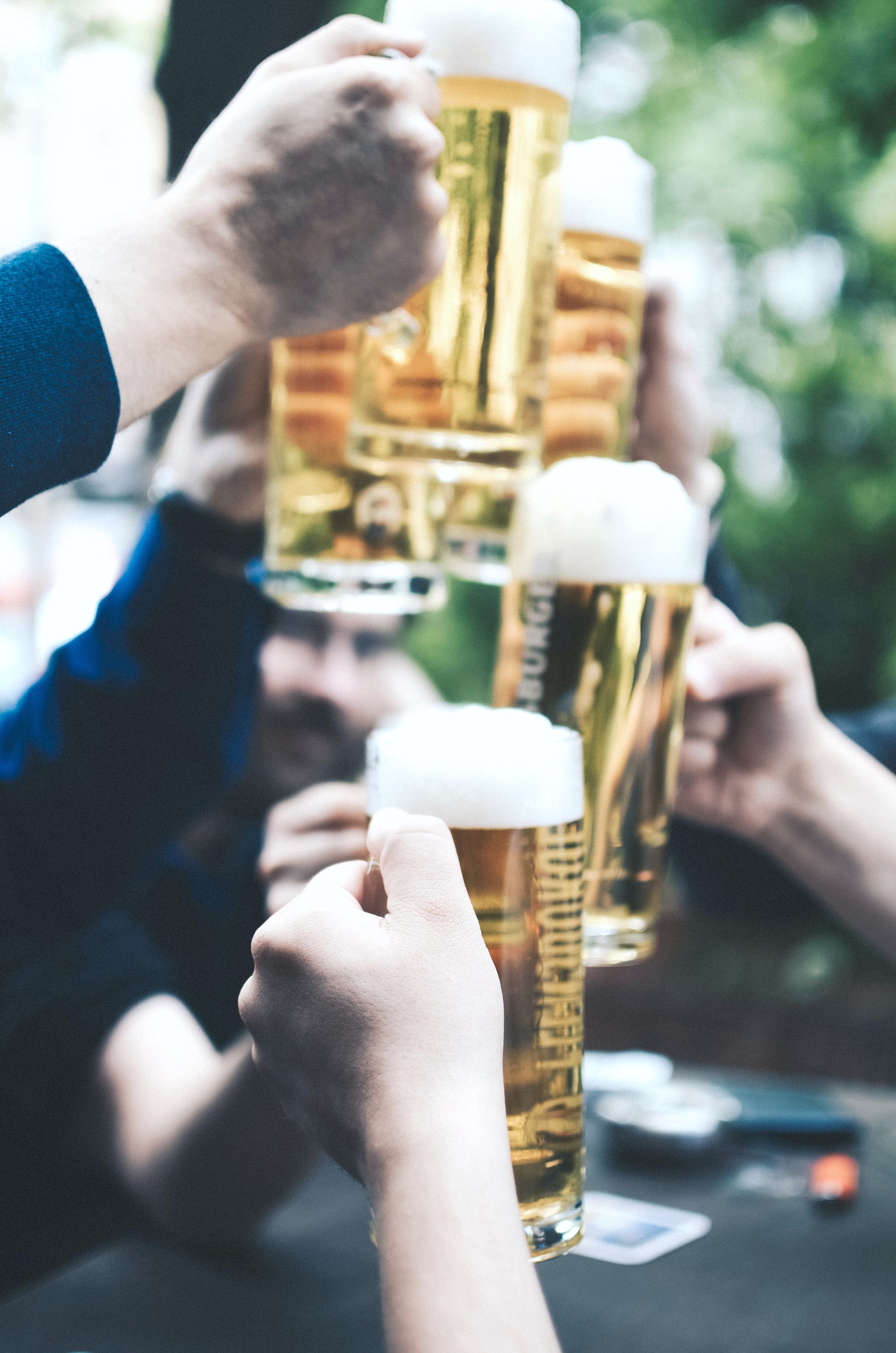 A group of men hold up pints of beer and cheer a good night out.