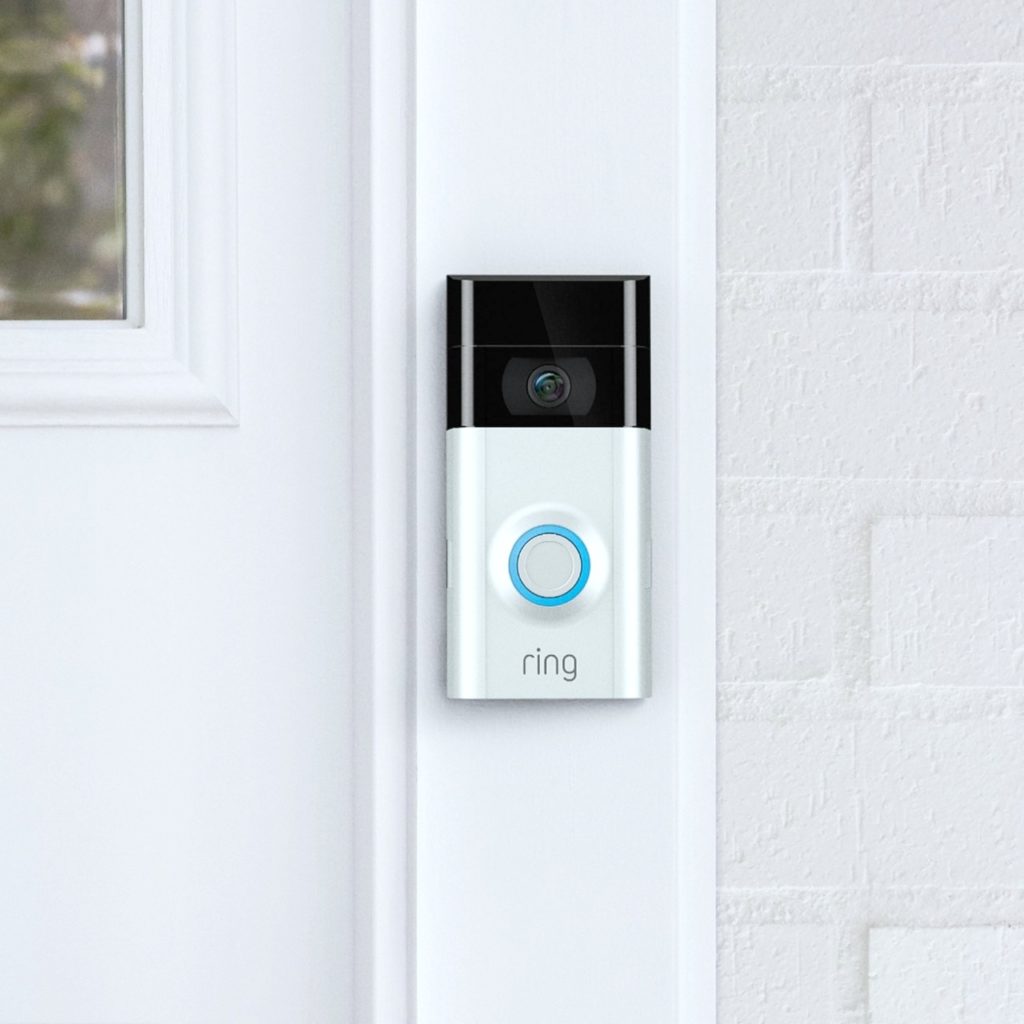 A close up of a ring doorbell is attached to a door pane.