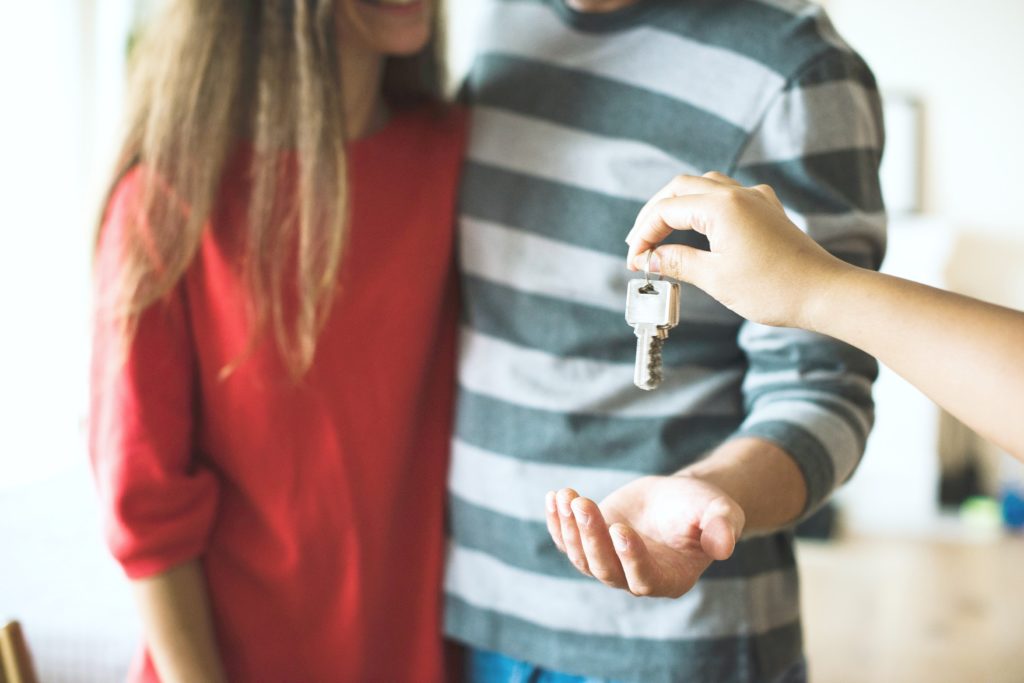 A young couple are being sold a home, they are having the keys handed to them.