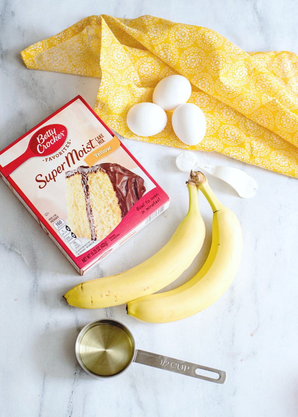 Ingredients to make Banana Bundt cake. Banana, cake mix, eggs, and oil are shown. 
