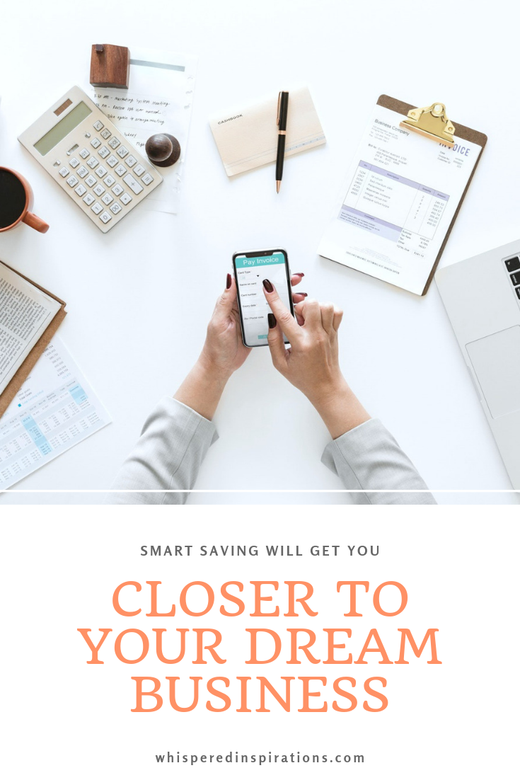 Woman surrounded by business necessities: laptop, coffee, invoices, paper, phone and more. A banner reads, "Smart saving tips to get you closer to your dream business.'