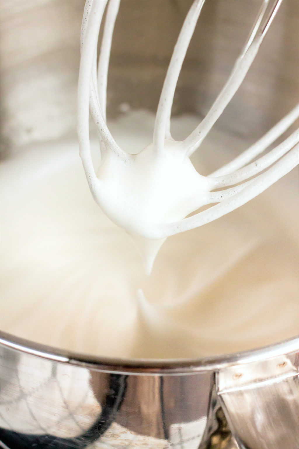 Whipped egg mixture is shown inside the electric mixer bowl, a whisk attachment is used. 