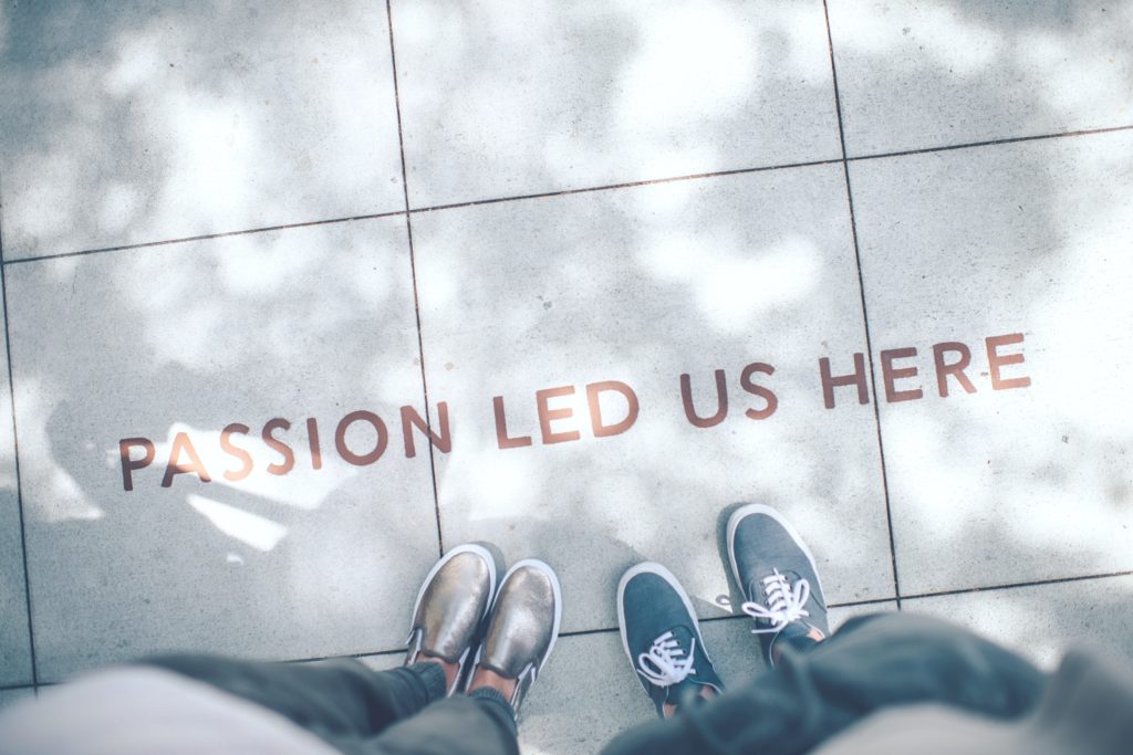 Two people starting their careers stand in front of a quote that says, "passion led us here."