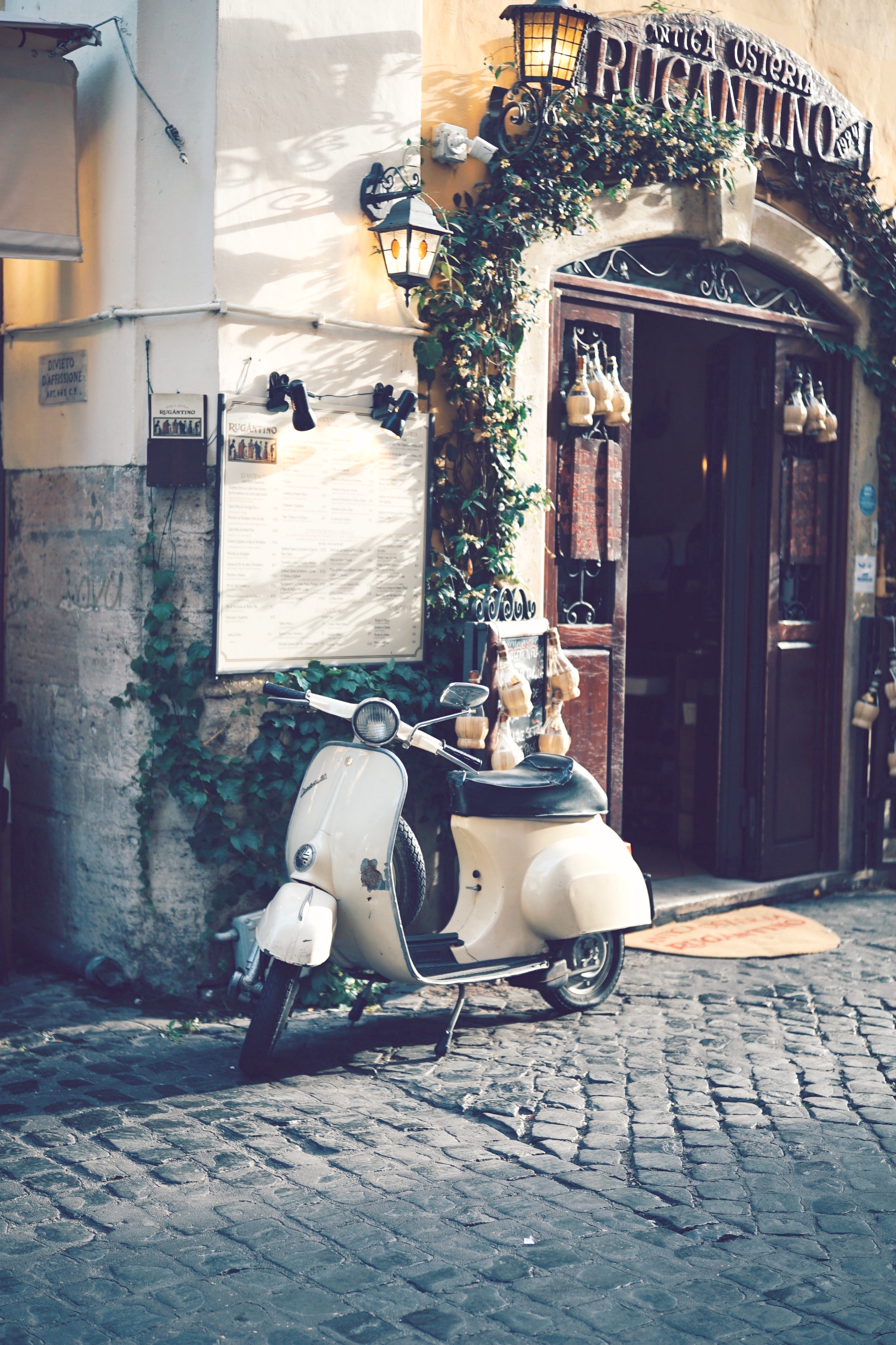 A motorbike parked in front of a restaurant on a European street.