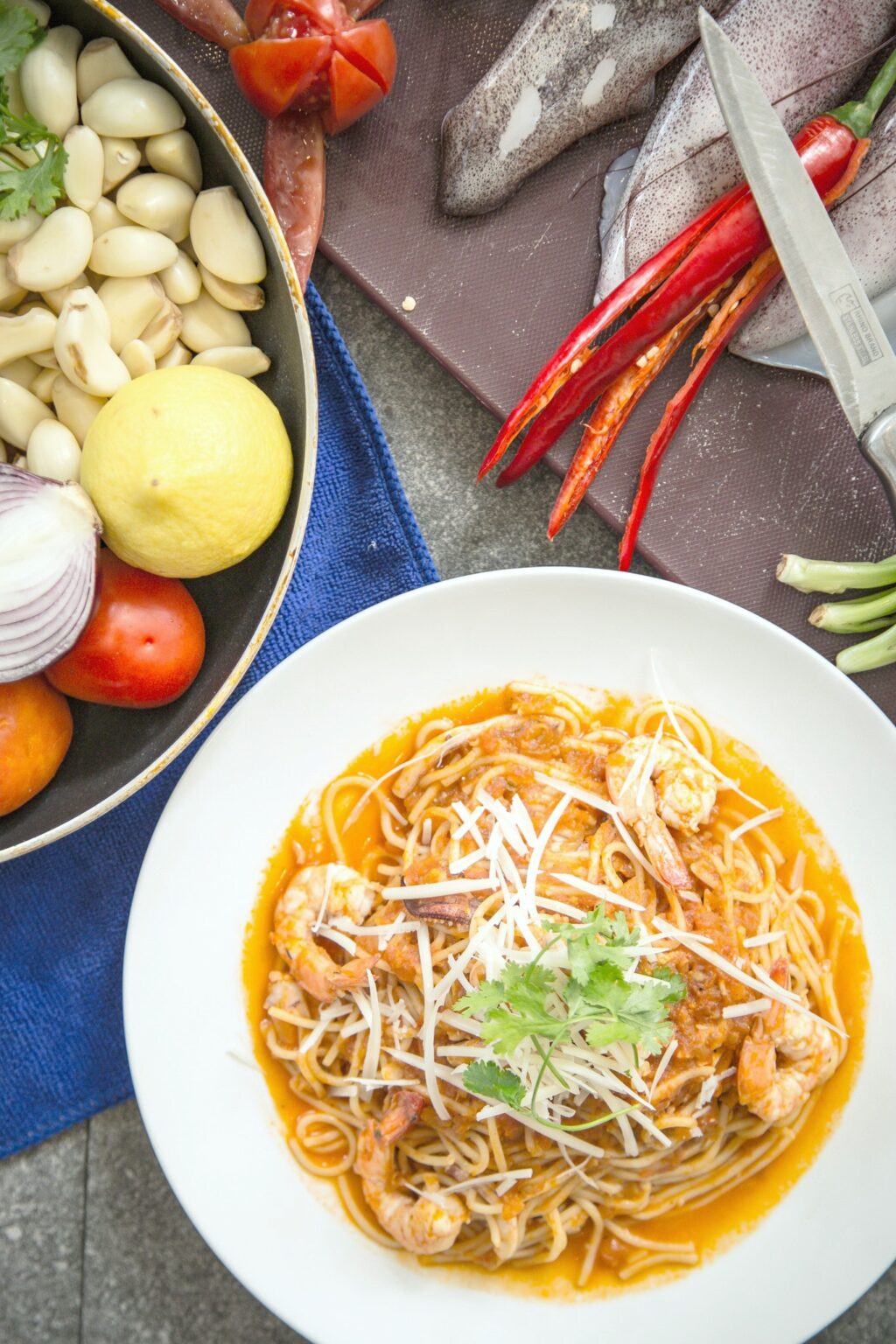 Shrimp pasta dish surrounded by ingredients to create dish.