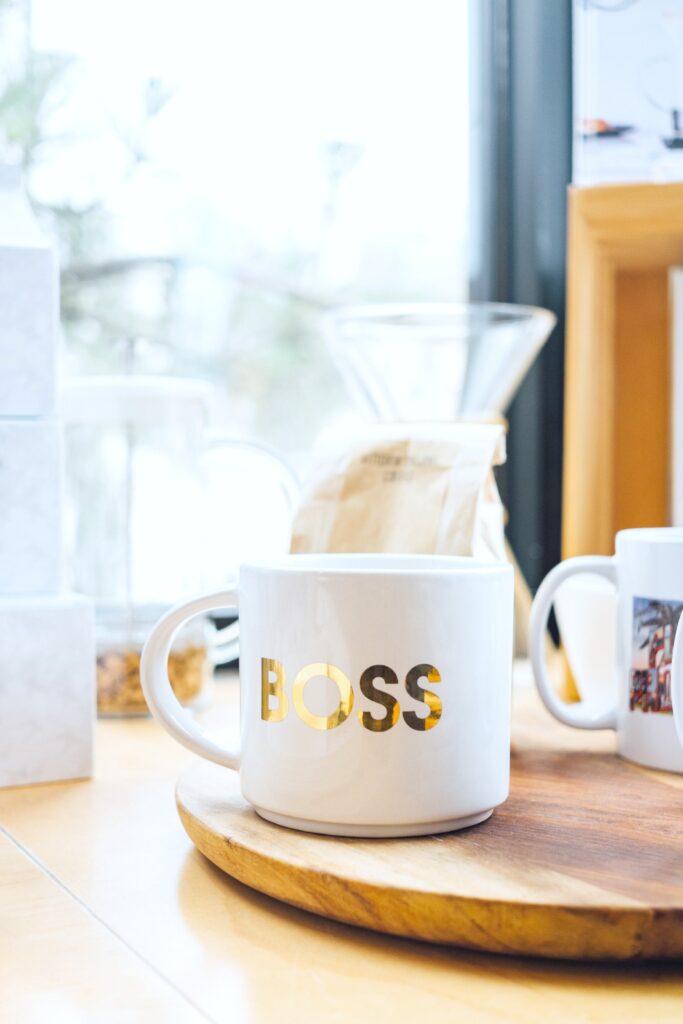 A mug that says Boss, on wooden tray on a kitchen table. 