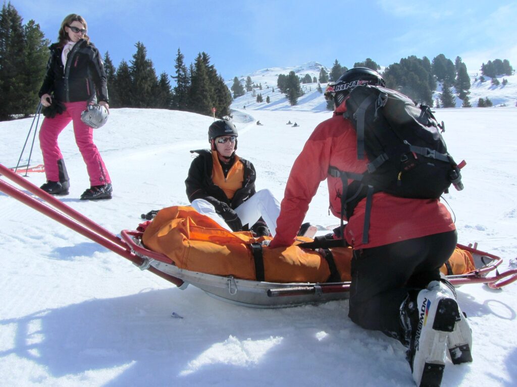 Skier that is injured is getting help from a medic. 