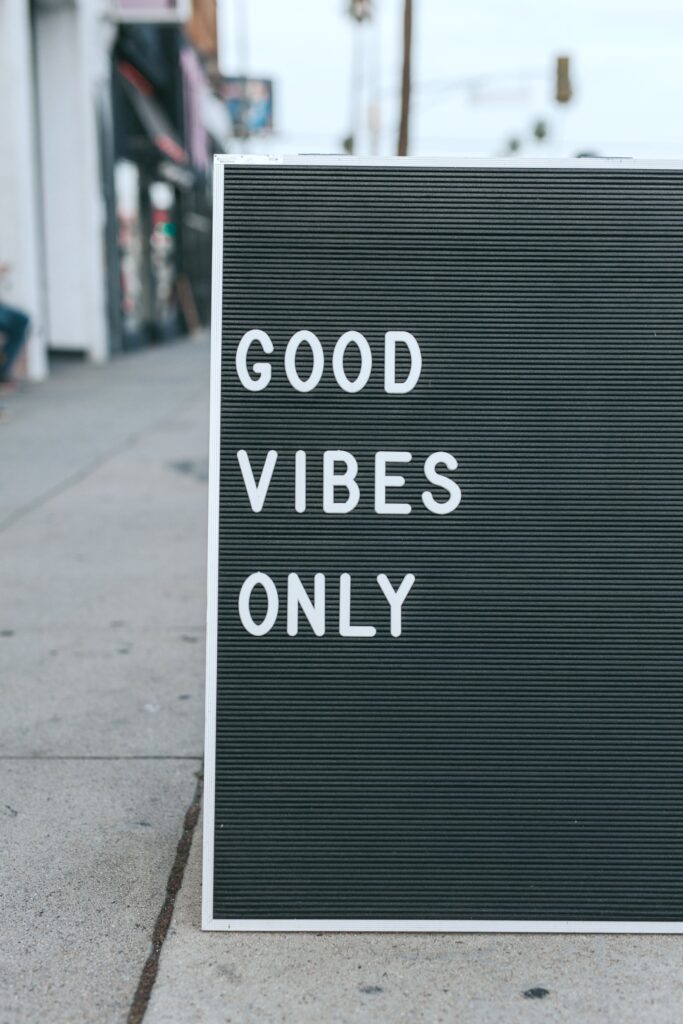 A black and white letterboard on a street that says, "Good Vibes."