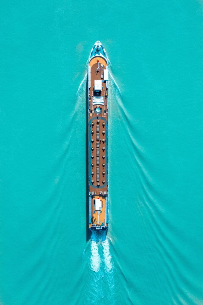 A cruise ship is seen on turquoise water and from birds eyes view.