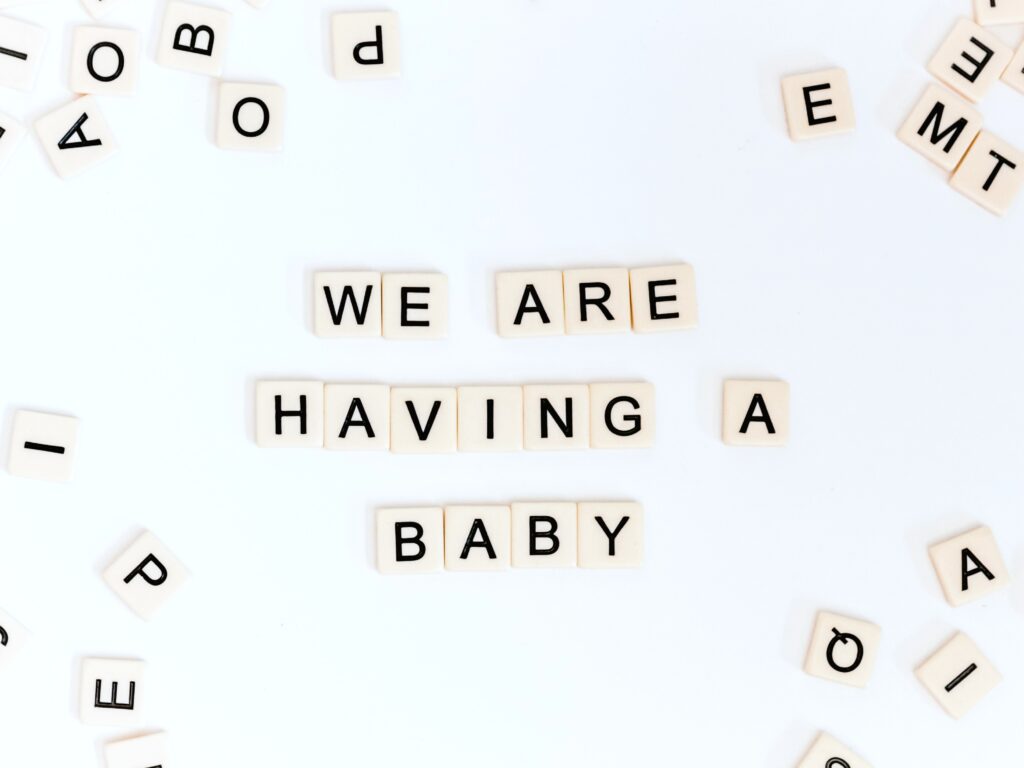 Scrabble pieces are placed to spell out, "we are having a baby."
