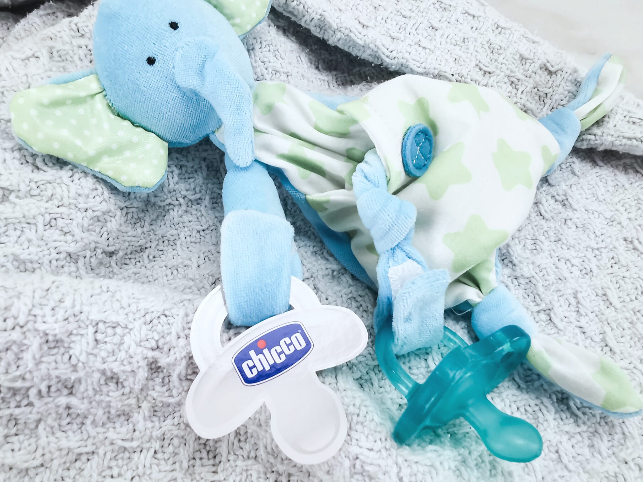 A blue blanket with a cute little teddy that holds the Chicco pacifier.
