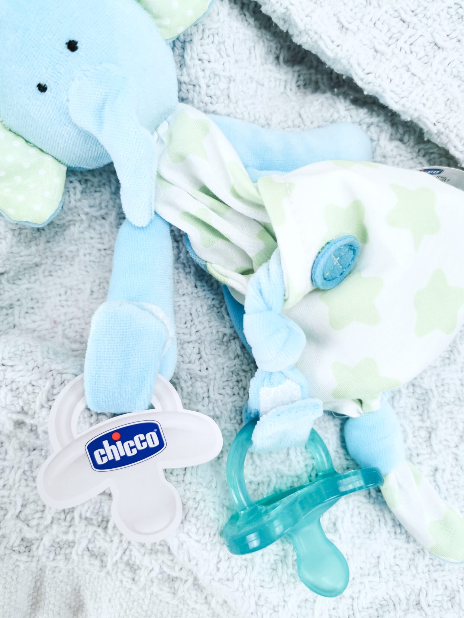 A blue blanket with a cute little teddy that holds the Chicco pacifier.