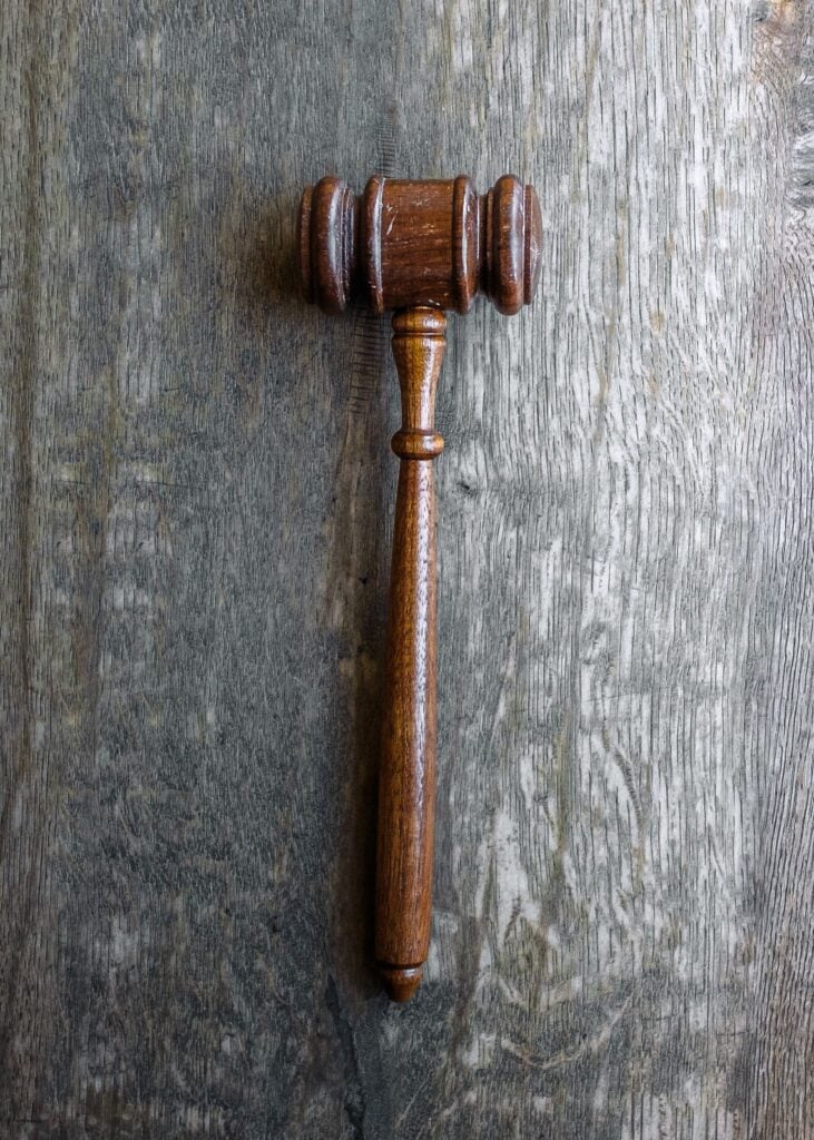 A gavel rests on a grey wooden top.