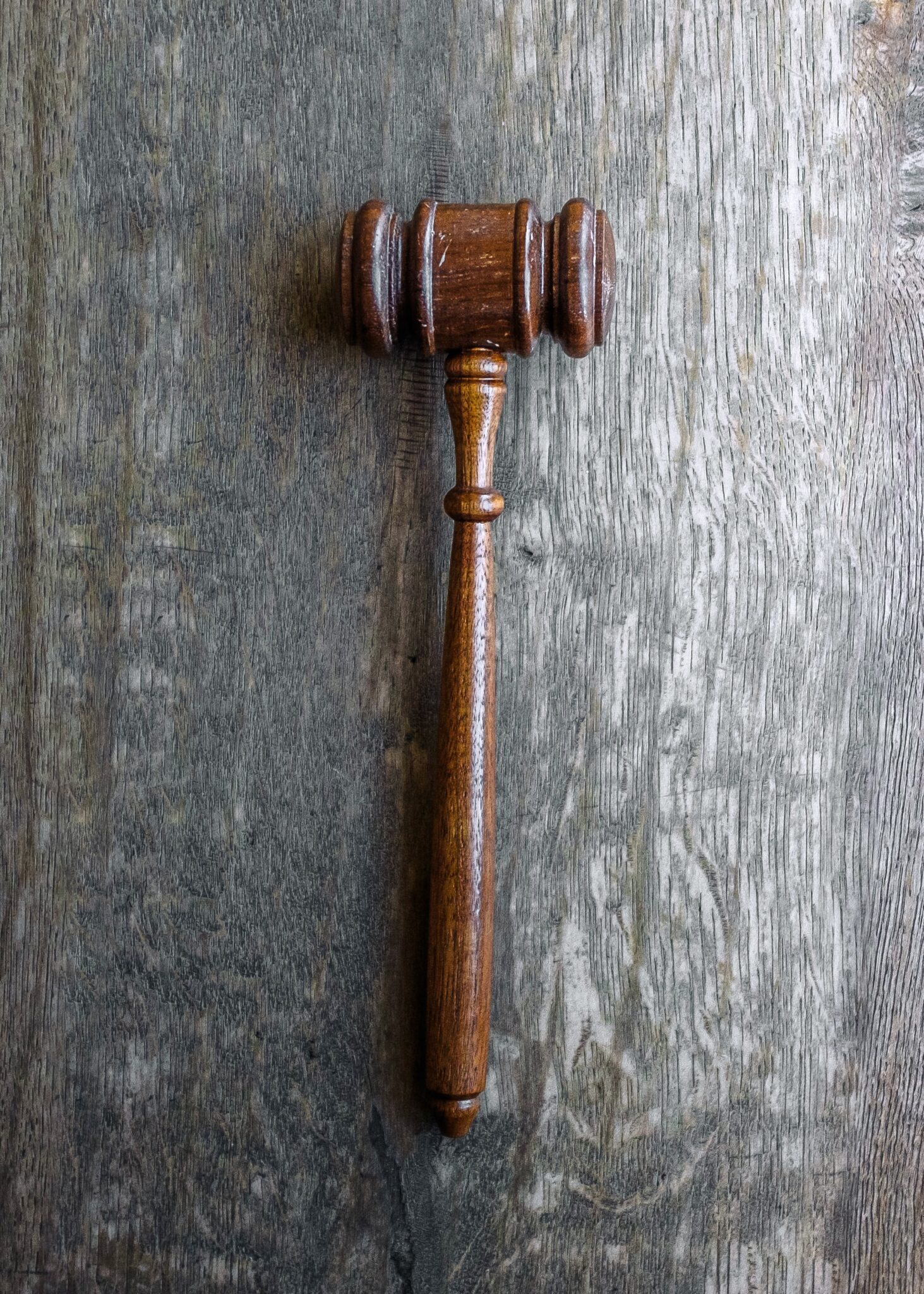 A gavel rests on a grey wooden top. This article covers what to look for when hiring a lawyer.