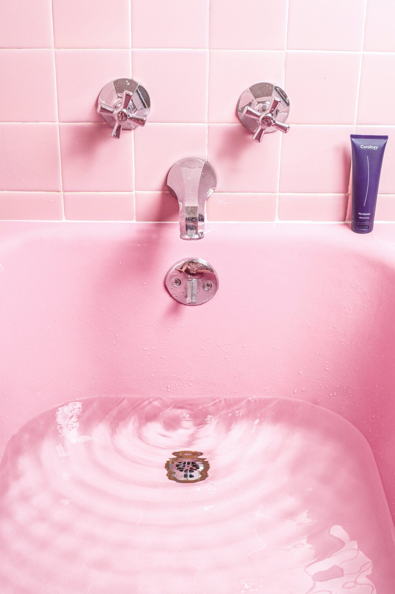 A pastel pink bathroom filled up a quarter. There are pink tiles too.