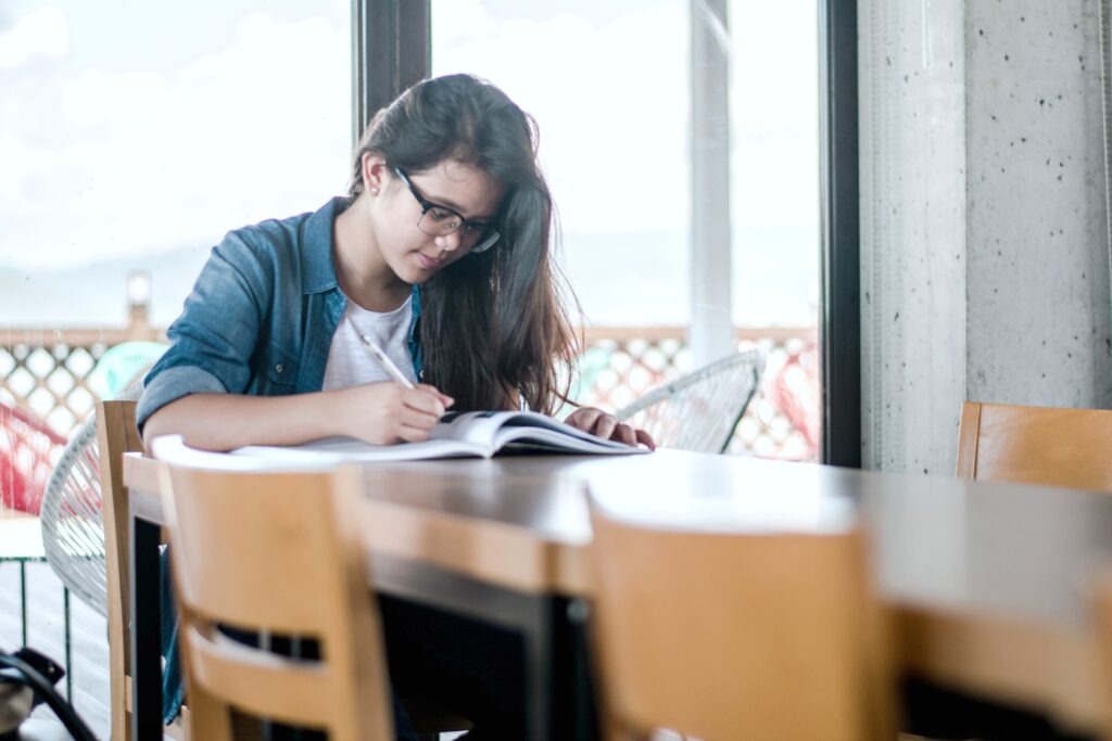 A student sits in a library by herself, studying for the SAT test.