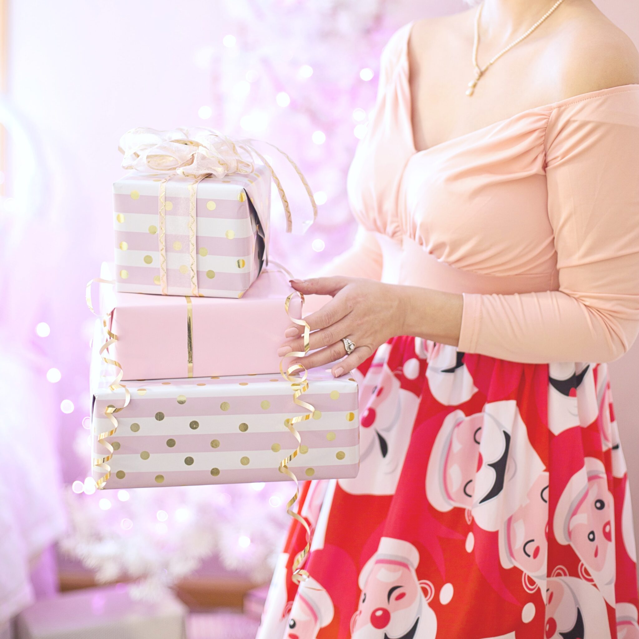 Woman holds gifts and her decollete is shown with a necklace. This article covers, 'How to choose the perfect jewellry for Christmas.'