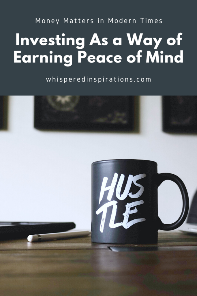 A mug with Hustle written on it sits on a wooden desk. This shows that investing can be a way to earn peace of mind. 