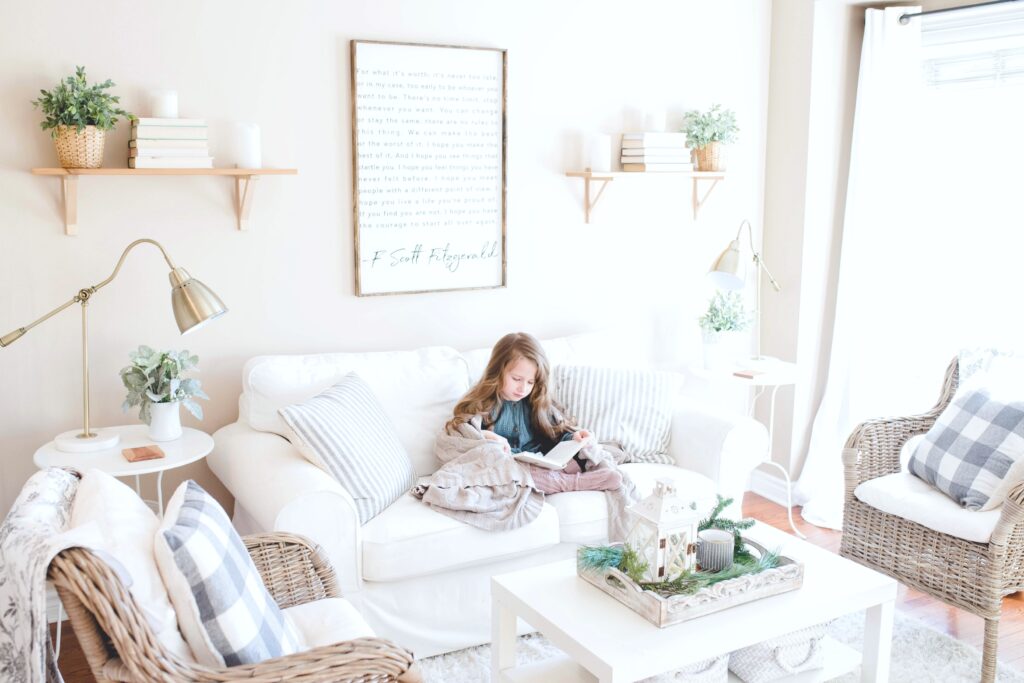 A little girl sits on a couch in her living room. The living room is bright and stylish.