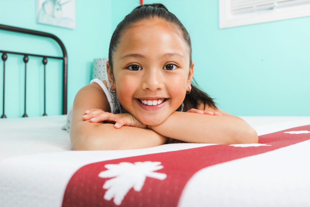 Mimi lays on her arms and tummy on the new Juno mattress. You can see the iconic Canadian liner.