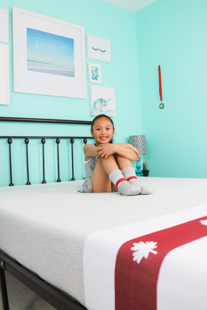 Mimi sits on her bed with her fave Canadiana socks on. She smiles!