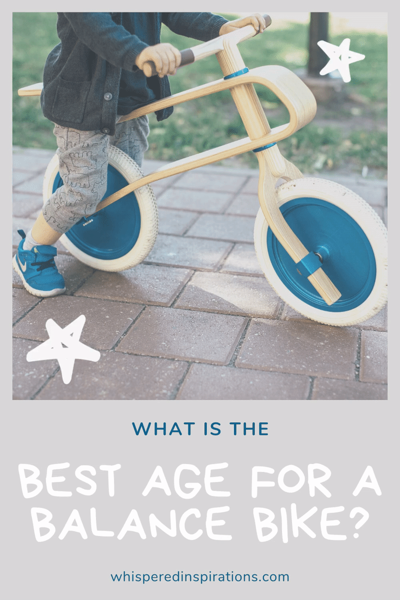 A close up of a little boy with blue Nike shoes, sitting on a wood and blue balance bike. A banner below reads, "What is the best age for a balance bike?"
