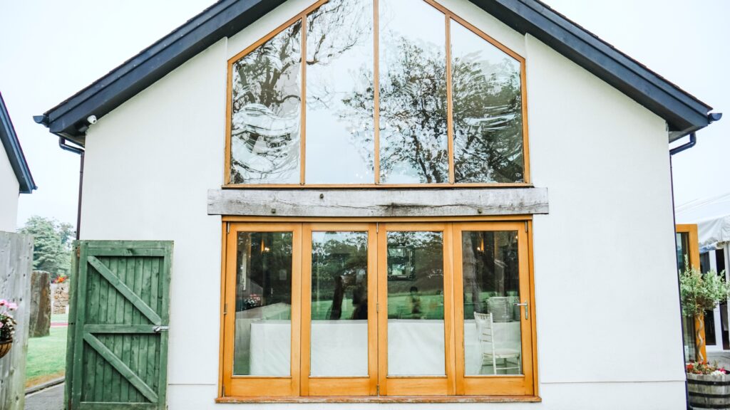 A backyard shows large windows and a wooden bi-fold door.