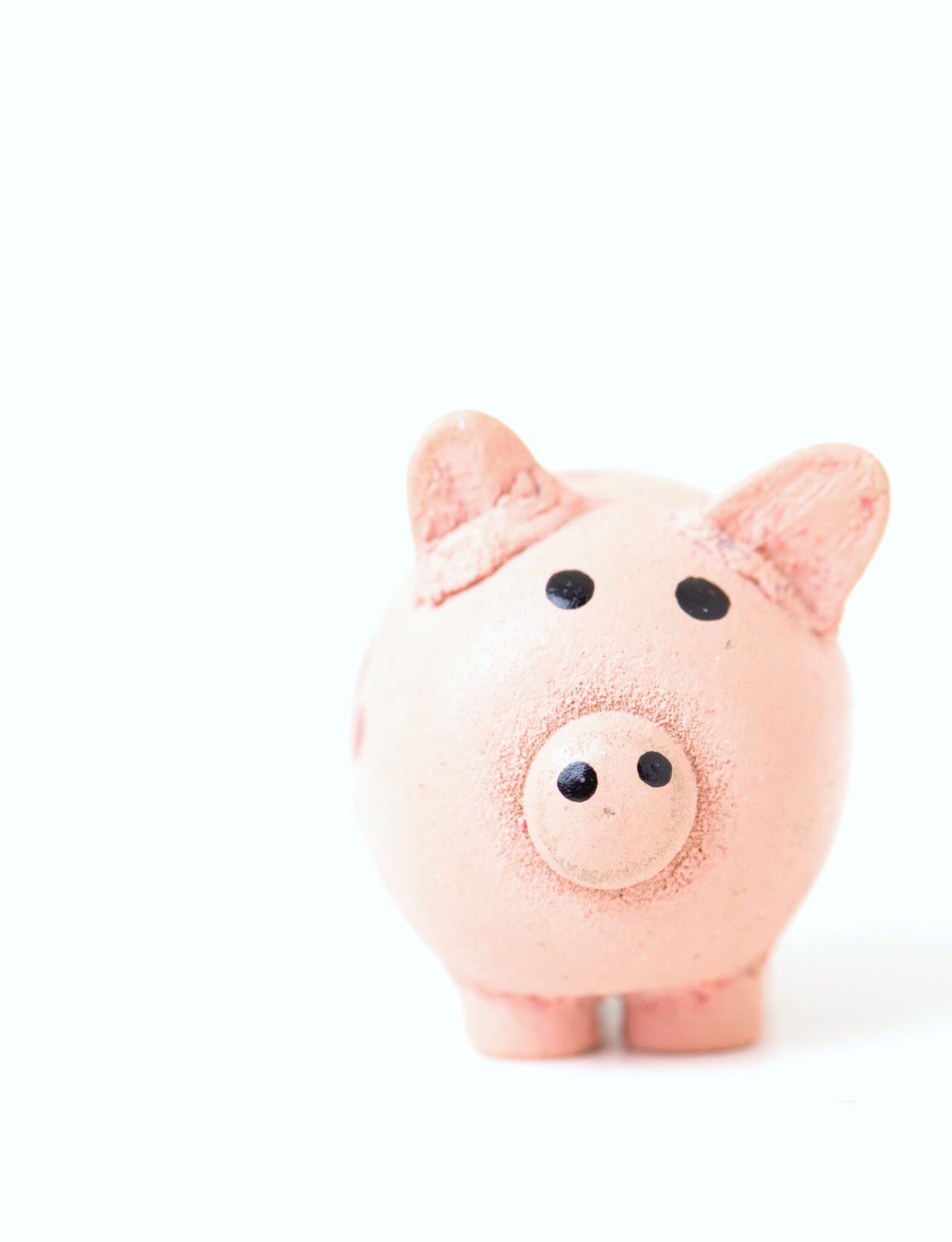 A white background with a pink, hand made piggy bank on the right.