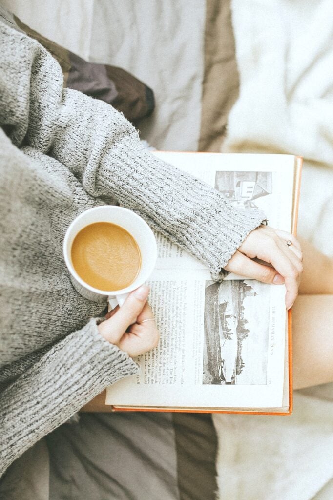 Woman reading a book while drinking coffee.
