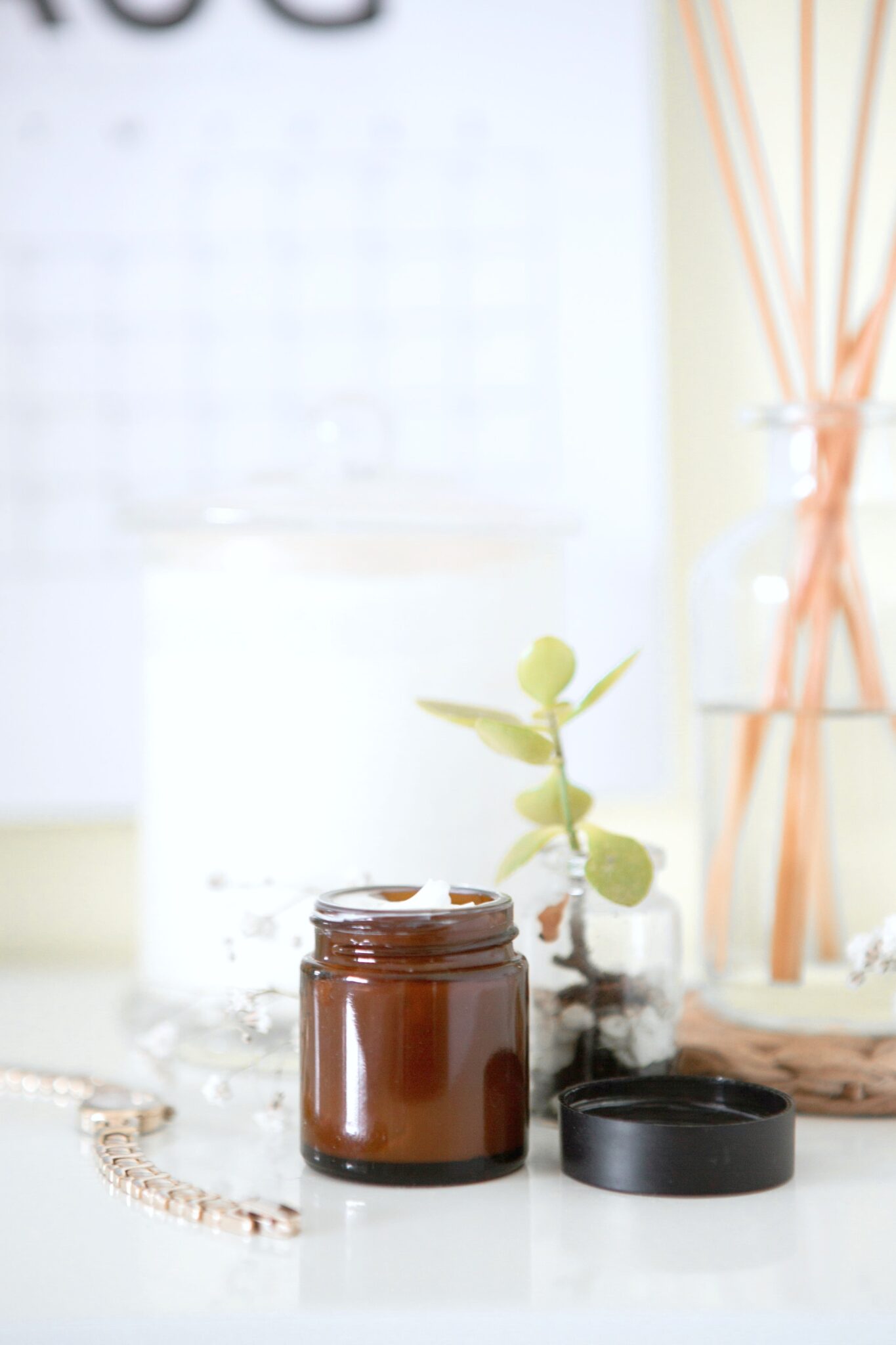 A vanity tabletop with an amber jar of cream, succulents, and essential oils are shown. 