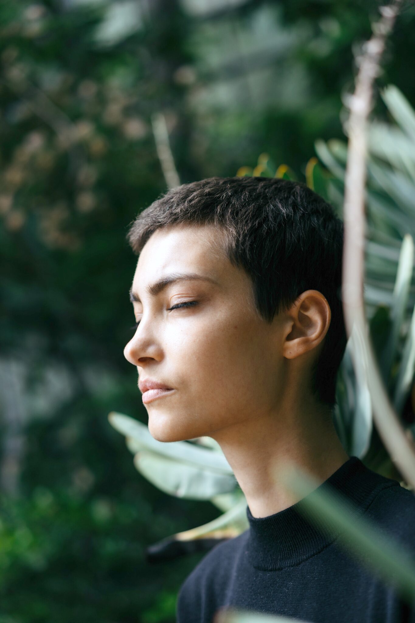 Woman in a forest with eyes closed and meditating. 