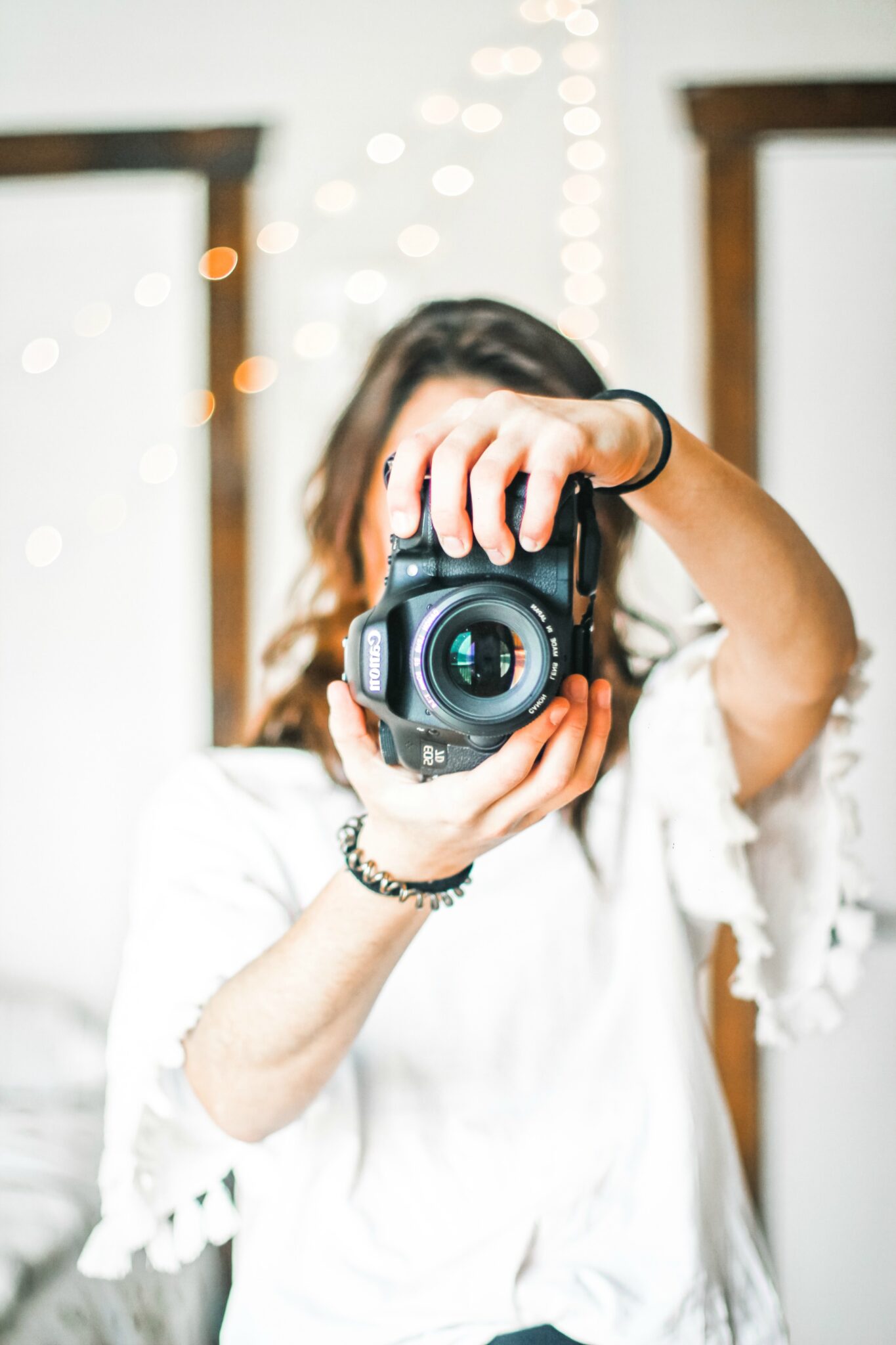 Woman holding camera and pointing it to the photographer. This picture is to show a photographer for the Ultimate Newborn Photography Guide.