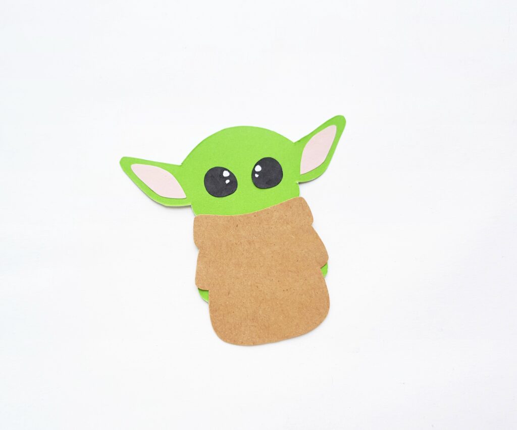 Brown robe is placed onto Baby Yoda body. 