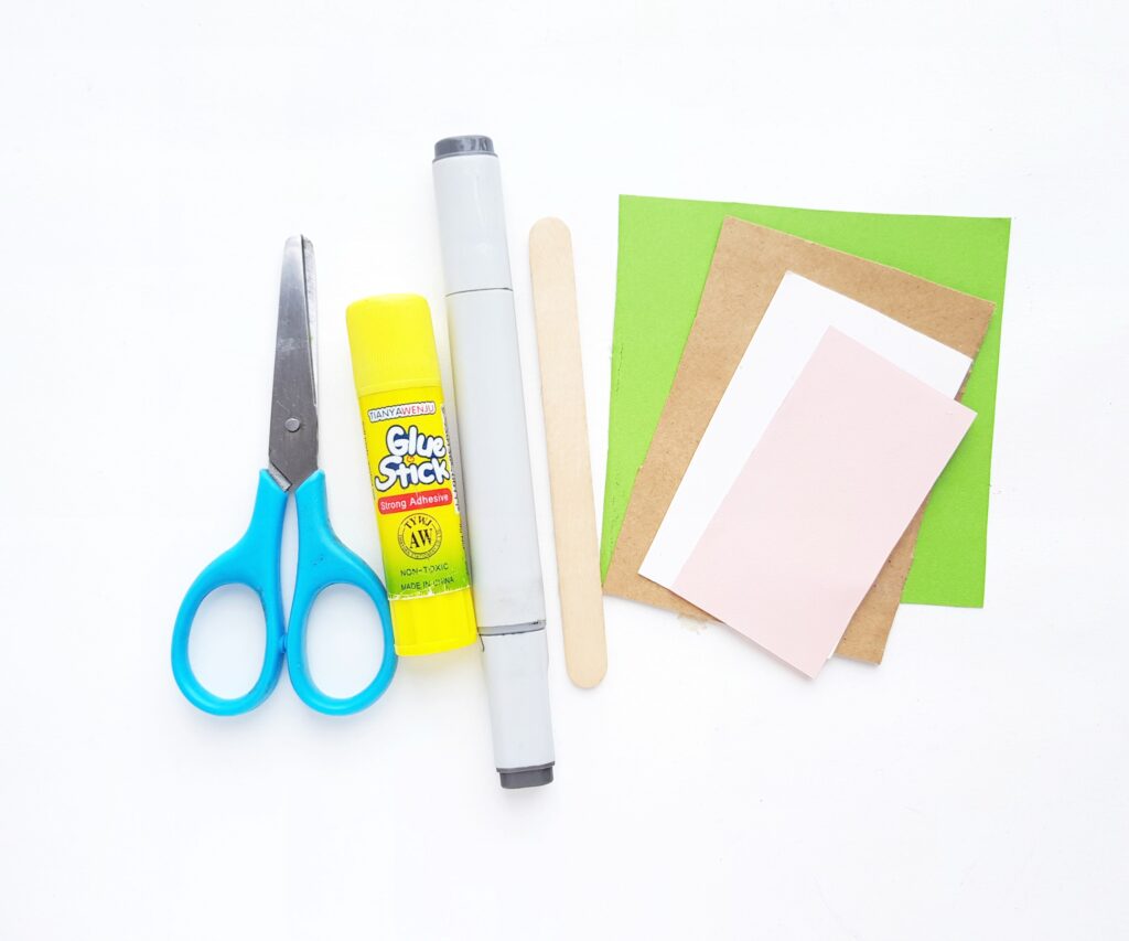 Supplies to make a Baby Yoda bookmark. Construction paper, glue, popsicle stick, scissors, and a marker.