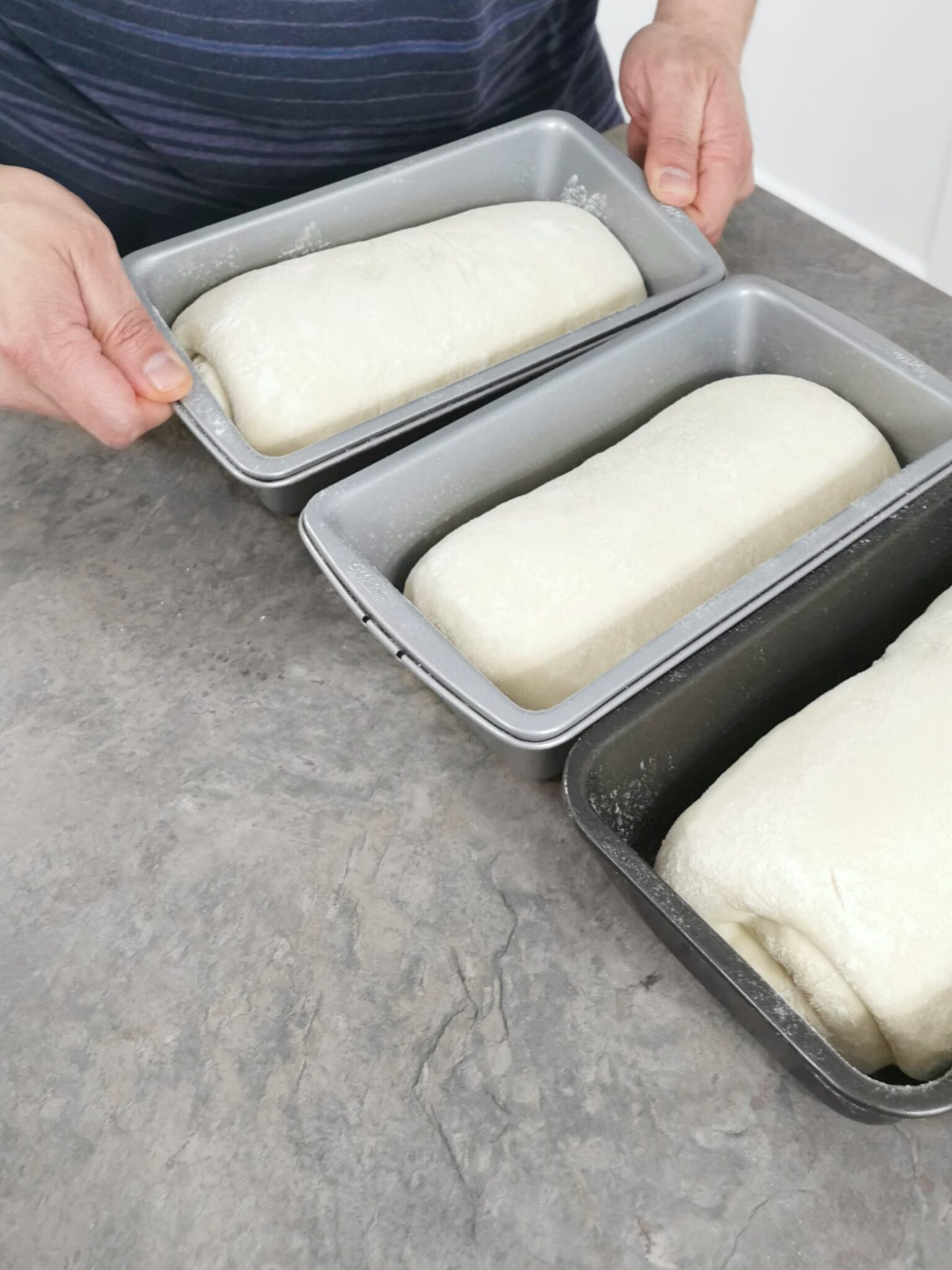 Unbaked loaves placed into pans.
