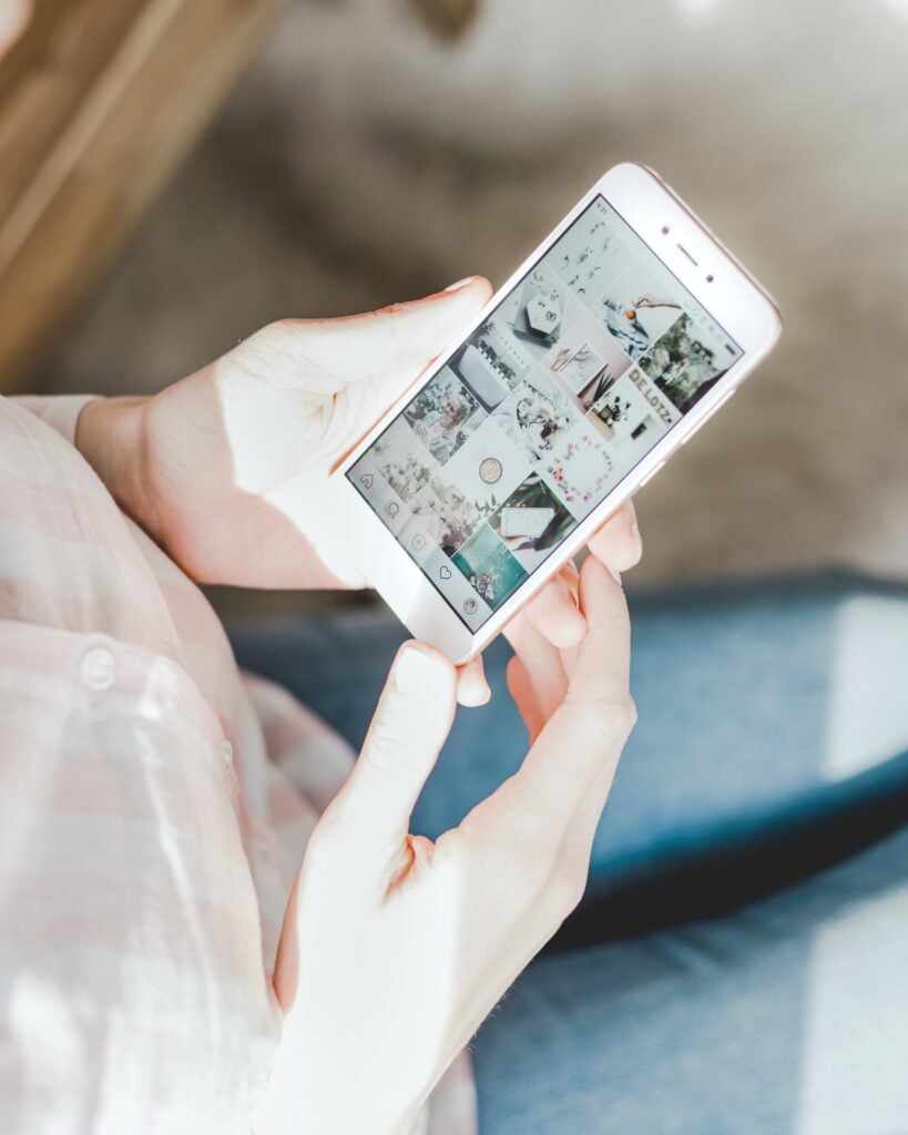 A woman holds an iPhone with the Instagram app open.