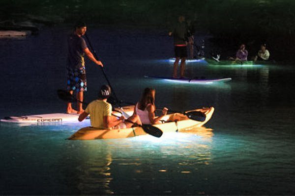 A couple kayak on a lake at night time.