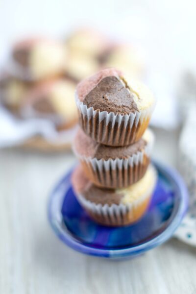 A stack of Neapolitan Ice Cream muffins on a blue dish. There is a plate behind them filled with muffins.