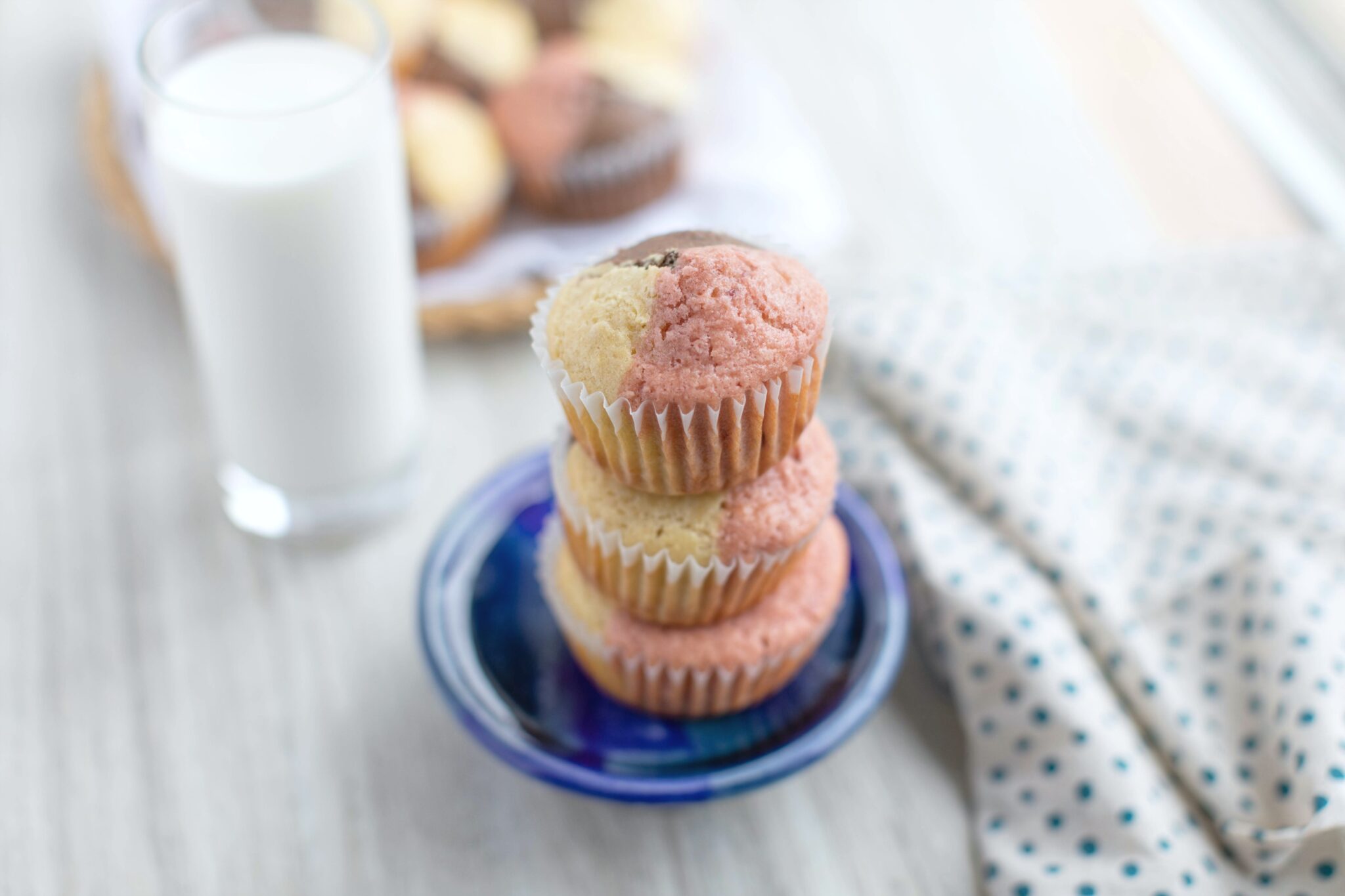 A stack of Neapolitan Ice Cream muffins with a glass of milk. 